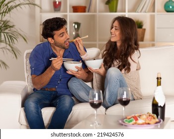 Happy Couple Eating Chinese Food And Drinking Wine At Home.