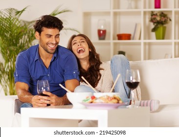 Happy Couple Eating Chinese Food And Drinking Wine At Home.