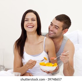 Happy Couple Eating Fruit And Orange Juice In Bed