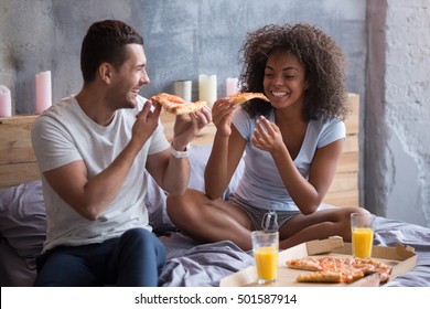 Happy Couple Eating Pizza In Bed