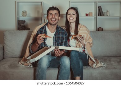 The Happy Couple Eating A Pizza And Watch A Movie On The Sofa
