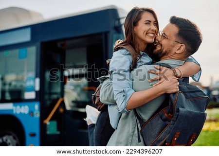 Happy couple embracing while meeting at bus station in the city. Copy space. 