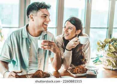Happy couple enjoying breakfast drinking coffee at bar cafeteria - Life style concept with guy and girl in love having date moment sitting at restaurant in the city centre - Powered by Shutterstock
