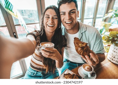 Happy couple enjoying breakfast drinking coffee at bar cafeteria - Life style concept with guy and girl in love having date moment sitting at restaurant in the city centre - Powered by Shutterstock