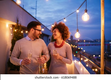 Happy Couple Enjoying Drinks And Balcony Party.