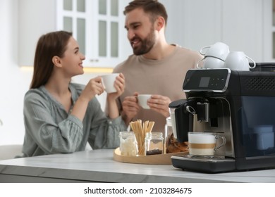 Happy Paar genießen frisch aromatischen Kaffee in der Küche, konzentrieren sich auf moderne Maschine