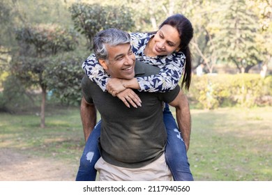 Happy couple enjoying piggyback ride in park