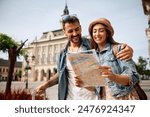 Happy couple enjoying in travel while exploring a map during their walk through the town. 