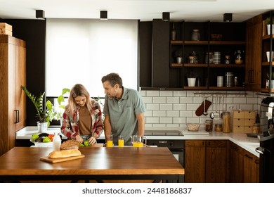 A happy couple enjoys a casual conversation with morning drinks in their sunny kitchen. - Powered by Shutterstock