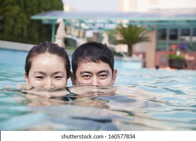 Happy Couple With Face Half Underwater In Pool Looking At Camera