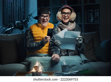 Happy couple finding the best energy deals online and saving money on their utility bills, they are comparing services and tariffs online on their smartphone