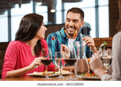 Happy Couple With Friends Eating At Restaurant