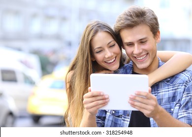 Happy Couple Or Friends Hugging And Sharing A Tablet In The Street