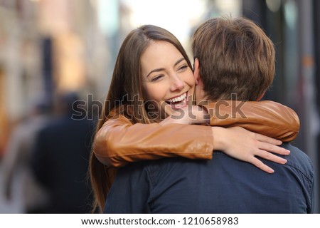 Happy couple of friends meeting and hugging in the street