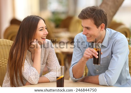 Happy couple or friends talking in a restaurant and looking each other