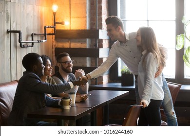 Happy Couple Get Acquainted With Multiracial People Coming At Meeting In Cafe, Young Man Introducing Handshaking African Guy From Diverse Friends Group, New Acquaintance And Making First Impression