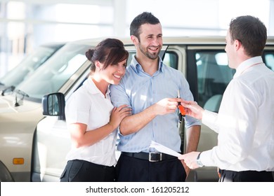 Happy Couple Getting Car Keys From A Car Seller