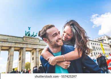Happy couple having fun in Berlin. Mixed race couple, a caucasian man giving a piggyback ride to his girlfriend, an asian woman. Happiness, lifestyle and tourism concepts