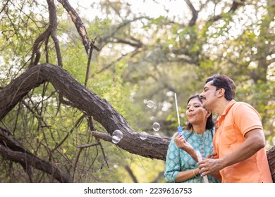 Happy couple having fun blowing bubbles at park. - Powered by Shutterstock