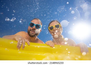 Happy couple having fun on summer vacation. People jumping in swimming pool against blue sky background. Active holiday concept. Spring break!