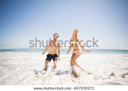 Happy couple having fun in water on shore at beach