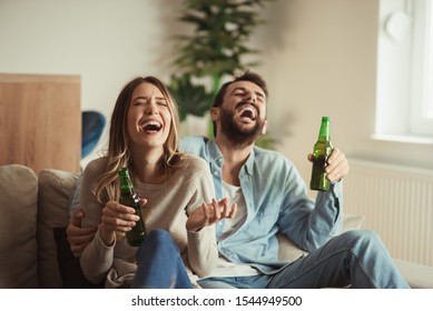 Happy Couple Having Fun While Drinking Beer At Home