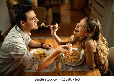 Happy couple having fun while feeding each other during a meal at dining table.  - Powered by Shutterstock