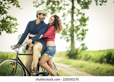 Happy couple having fun while biking on a country road