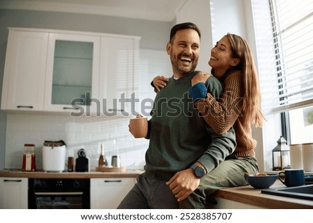 Happy couple having fun while drinking coffee in the kitchen.