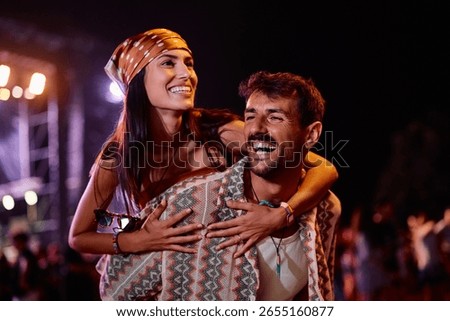 Happy couple having fun while attending summer music festival at night.