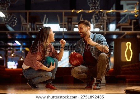 Happy couple having fun while celebrating success while bowling at the club. 