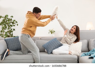 Happy couple having pillow fight in living room - Powered by Shutterstock