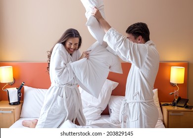 Happy Couple Having Pillow Fight In Hotel Room