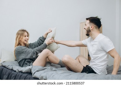 Happy Couple Having Pillow Fight In Hotel Room