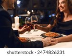 Happy couple having romantic dinner in restaurant, eating pasta and drinking red wine. Happy Valentine day concept