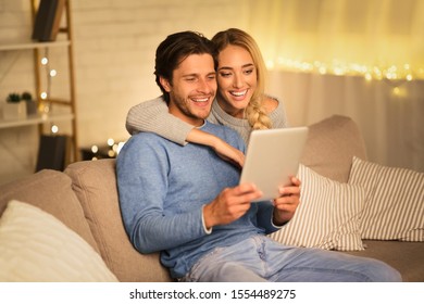 Happy couple having video-call on tablet, spending winter evening at home