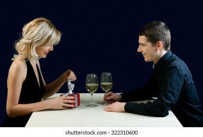 Happy Couple Having Wine In The Restaurant. Woman Unwrapping Valentine's Present.