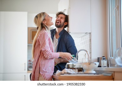A happy couple having wonderful time while washing dishes in a cheerful atmosphere together. Kitchen, housework, home, relationship