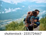 Happy couple of hikers hugging each other as they celebrate climbing to the top of a hill. Copy space. 