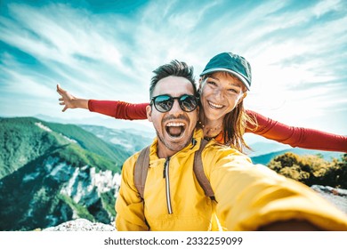 Happy couple of hikers taking selfie portrait on the top of the mountain - Smiling tourists enjoying summer day out - Boyfriend and girlfriend having summertime activity together - Life style concept - Powered by Shutterstock