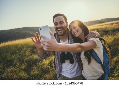 Happy couple is hiking in mountain. They are taking selfie. - Powered by Shutterstock