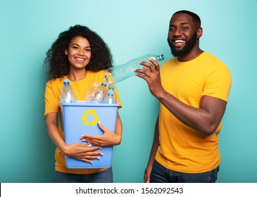 Happy couple hold a plastic container with bottles over a light blue color. Concept of ecology, conservation, recycling and sustainability - Powered by Shutterstock