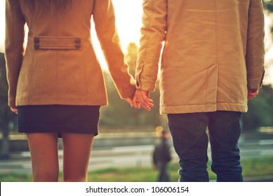 Happy couple holding hands looking in the sunset
