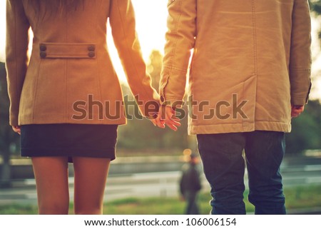 Happy couple holding hands looking in the sunset