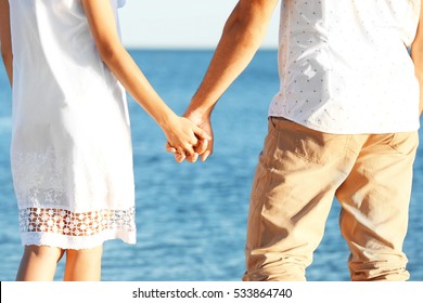 Happy couple holding hands on sea background