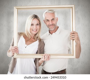 Happy couple holding a picture frame against weathered surface - Powered by Shutterstock