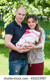 Happy Couple Holding Their Newborn Daughter In Her Arms. Outdoors