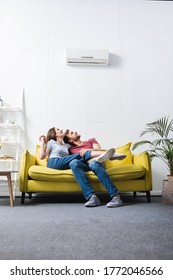 happy couple at home with air conditioner