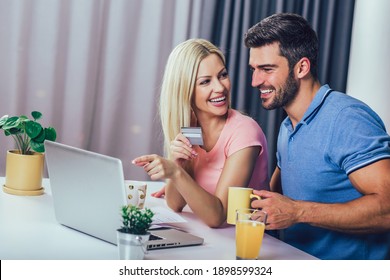 Happy Couple At Home Paying Bills With Laptop And Credit Card