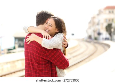 Happy couple hugging in a train station after arrival